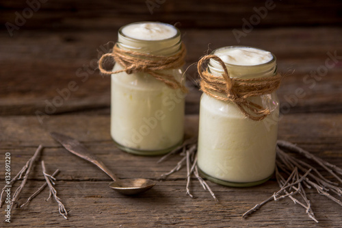 Yogurt in jars on the wooden table with dried plant