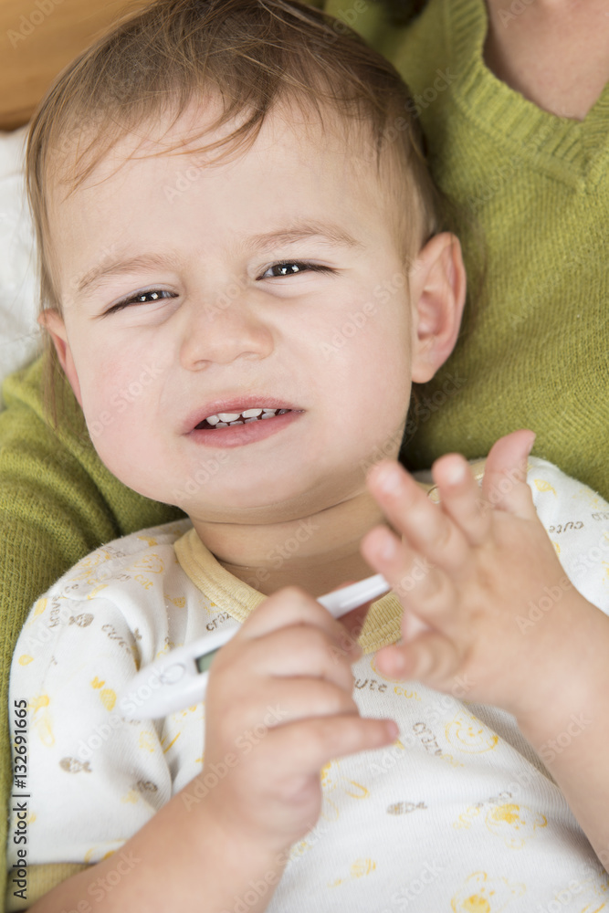 Crying baby with fever holding thermomether foto de Stock Adobe Stock