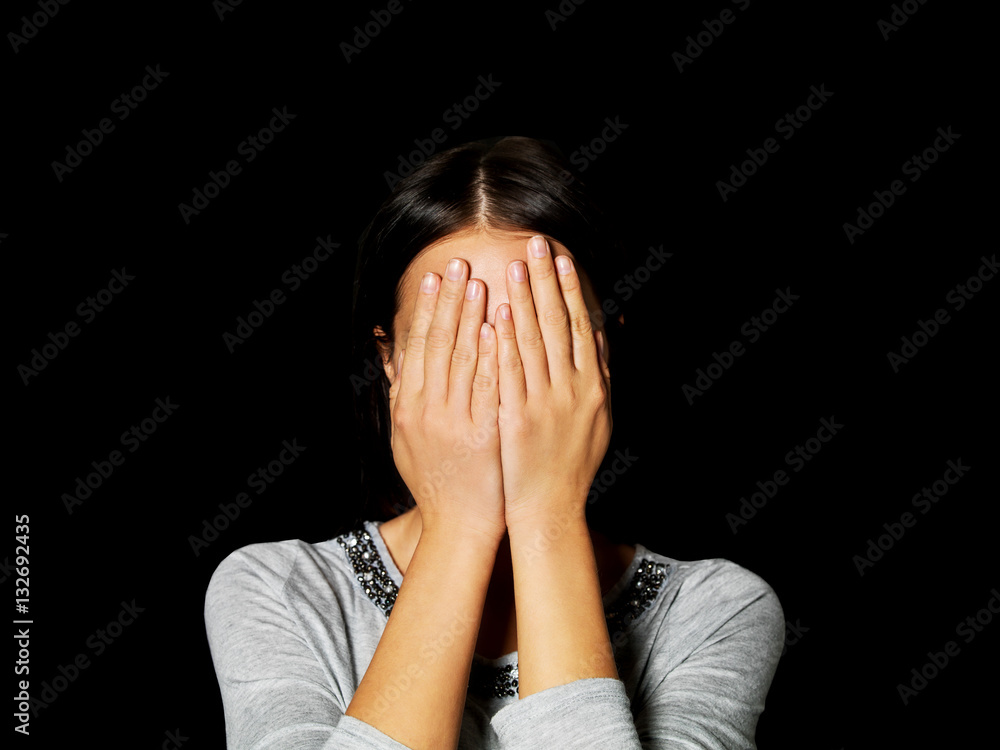 Young woman covering her face with her hands Young woman covering her face with her hands
