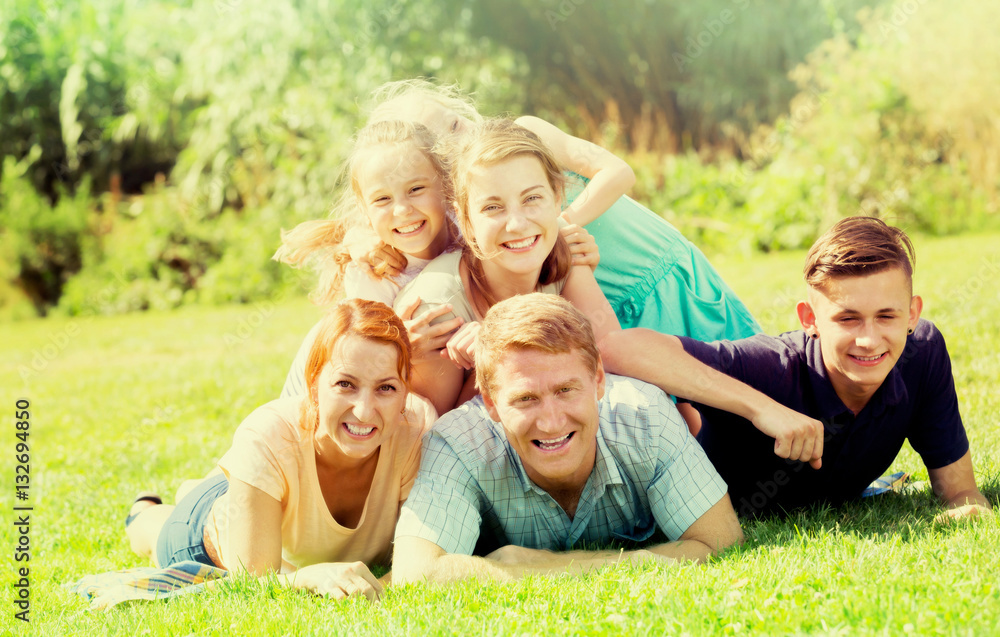 Fototapeta premium Happy man and woman with four kids lying in park