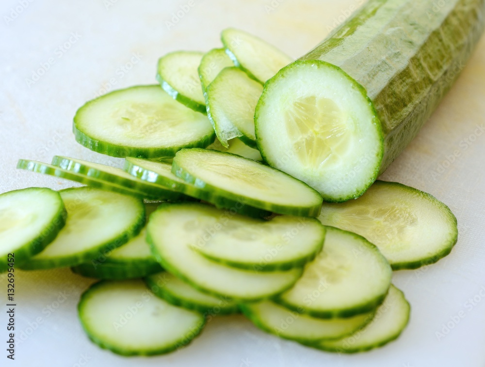 Chopped cucumber into small slices on white cutting board. Chopped cucumber into small slices on white cutting board.