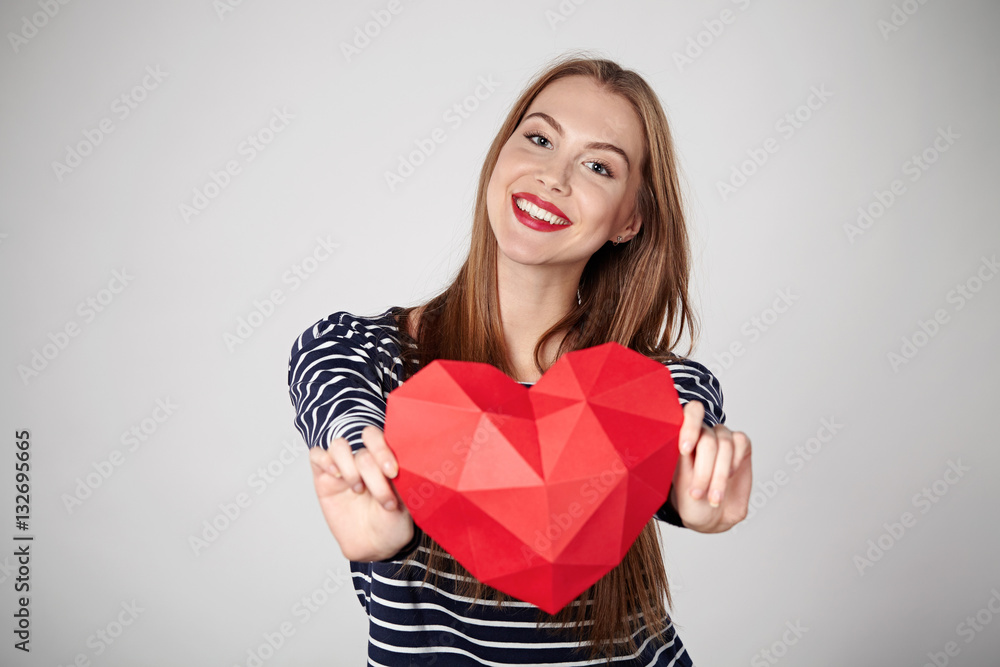 Smiling woman holding red polygonal paper heart shape Smiling woman holding red polygonal paper heart shape
