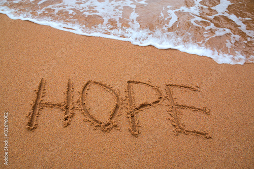 written words " hope " on sand of beach with wave on background © Natalia Liubinetska