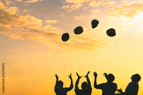 Silhoutte of construction engineers throwing safety helmets upward on golden sunset sky, multiethnic diverse group, engineering industry or success teamwork celebration concept