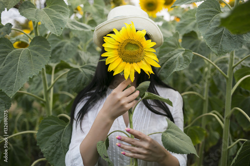 Beauty joyful teenage girl in panama with sunflower in hands enjoying nature summer sunflower field. Summer nature concept