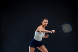 Portrait of beautiful girl tennis player with a racket on dark background