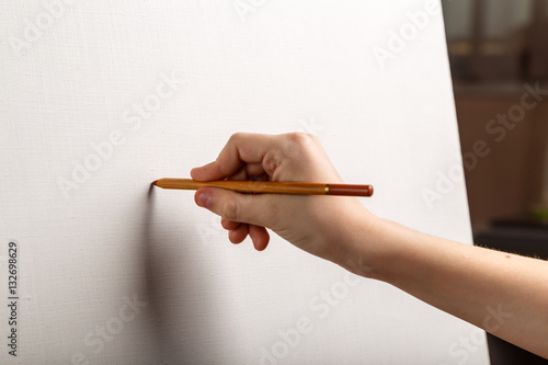 карандаш в руке подростка, рисующего на чистом холсте 