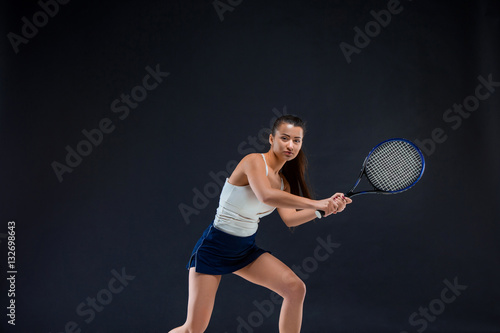 Portrait of beautiful girl tennis player with a racket on dark background © master1305