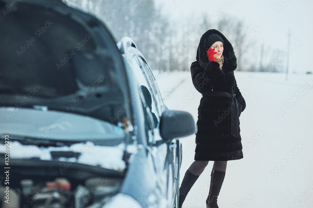 girl on the winter road is calling the phone near the car girl on the winter road is calling the phone near the car
