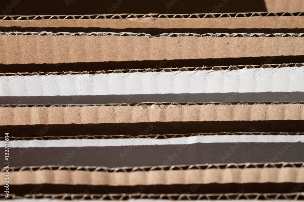 Obraz premium Texture of layered brown cardboard side. Folded cardboard boxes. Wavy paper texture on sunlight with copy space.