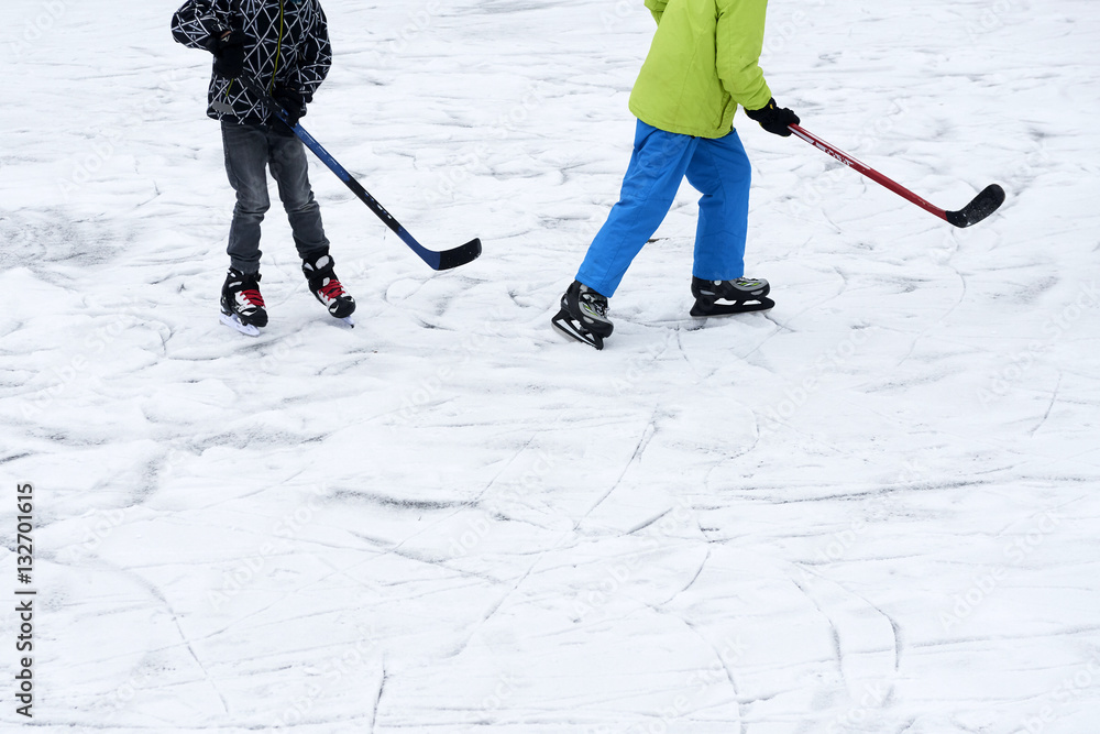Fototapeta premium A group of children playing ice hockey at the skating rink outside in winter.
