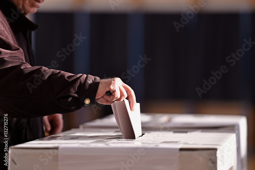 Person casting vote into ballot box photo