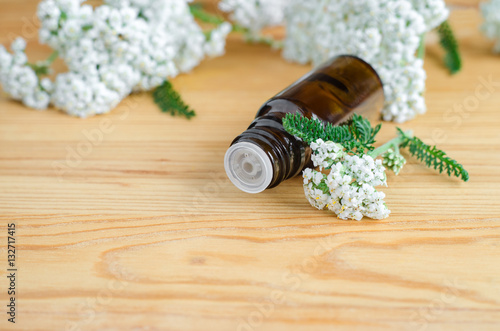 Small bottle of essential yarrow oil on a wooden background