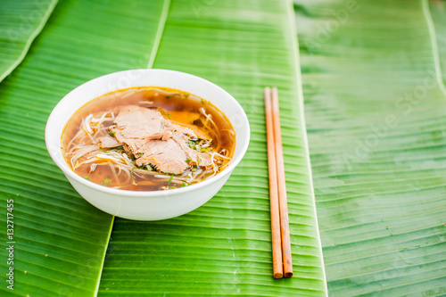 Bild auf Leinwand A bowl of Traditional Vietnamese beef soup Pho Bo on banana leaf background