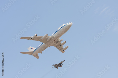  Il-80 command center for Russian officials and Mig-29 jet fighter fly against blue sky background 