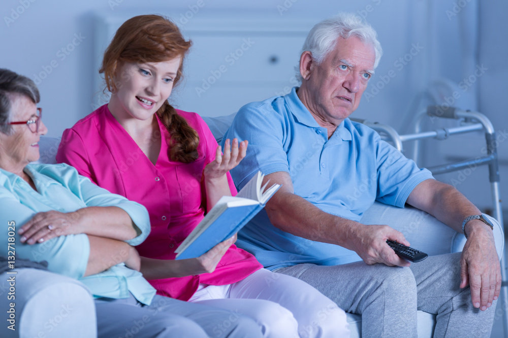 Caregiver reading book to patients Caregiver reading book to patients