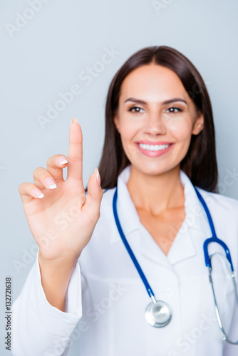 Young happy female doctor touching virtual screen