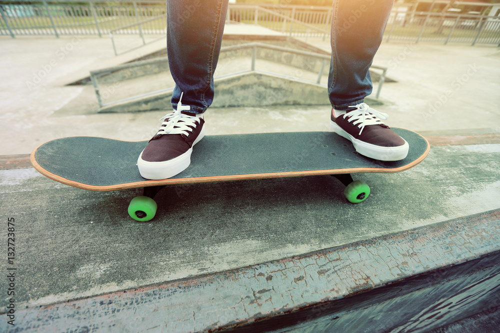 young skateboarder legs riding skateboard at skatepark