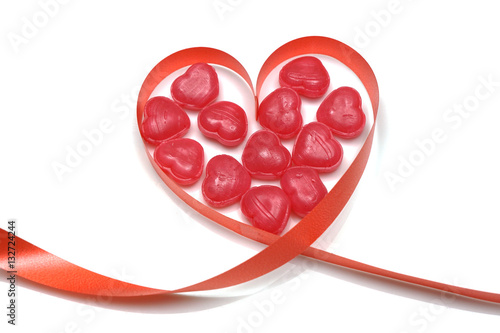 red ribbon and candy toffee heart shape isolated on white backgr