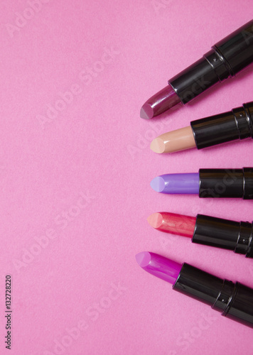 Assorted color lip stick make up on a hot pink background with empty space at side