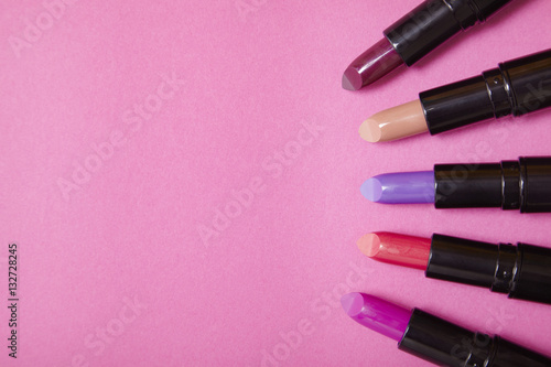 Assorted color lip stick make up on a hot pink background with blank space at side