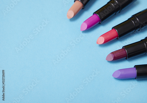 Lipstick make up arranged on a bright blue background with blank space at side