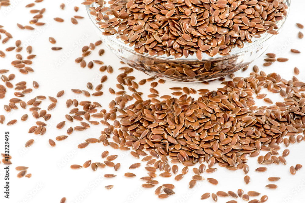 Flax seeds in transparent bowl on white background

