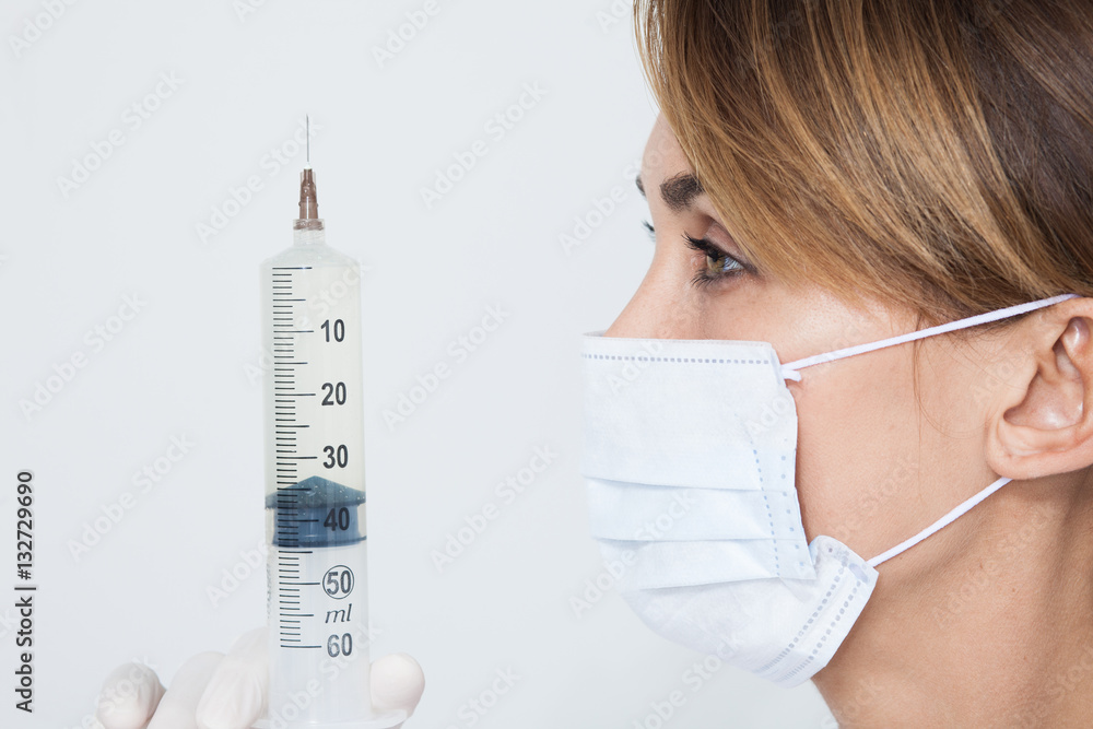 femme médecin avec un masque et une grosse seringue Stock Photo