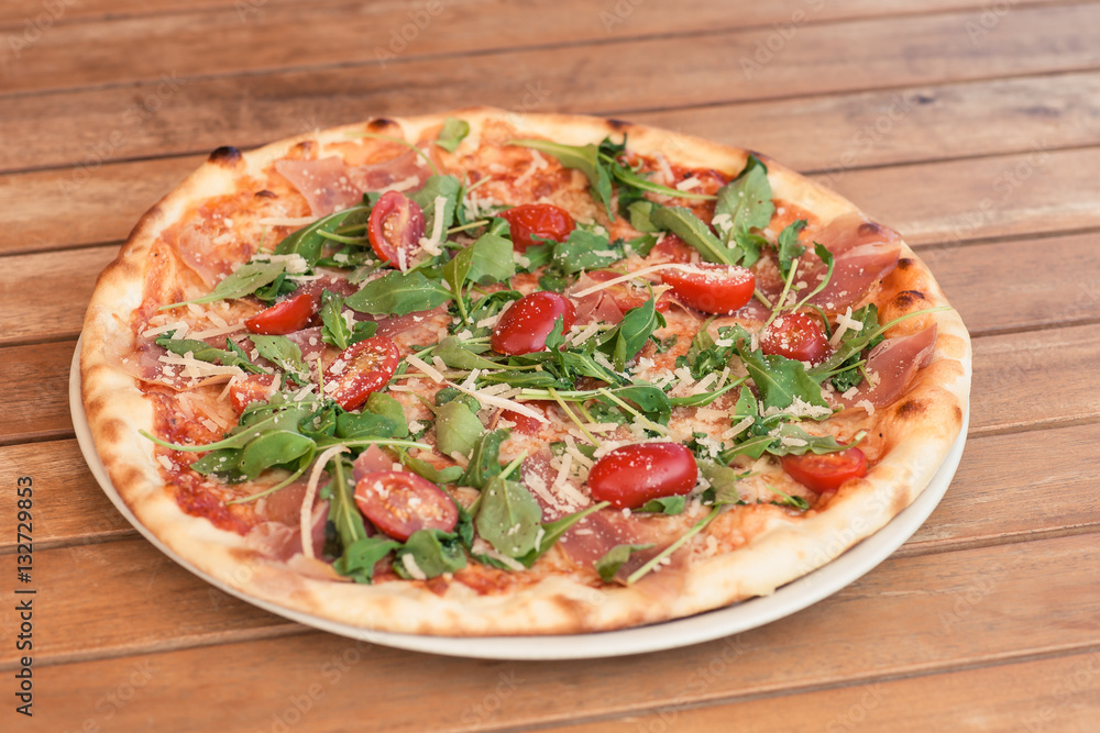 pizza on a wooden table with tomato and cheese pizza on a wooden table with tomato and cheese