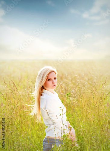 Young pretty woman standing in field in sunny day