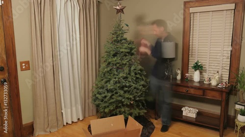 Time lapse of a man taking down a Christmas tree with holiday decorations. Shot in 4K UHD.