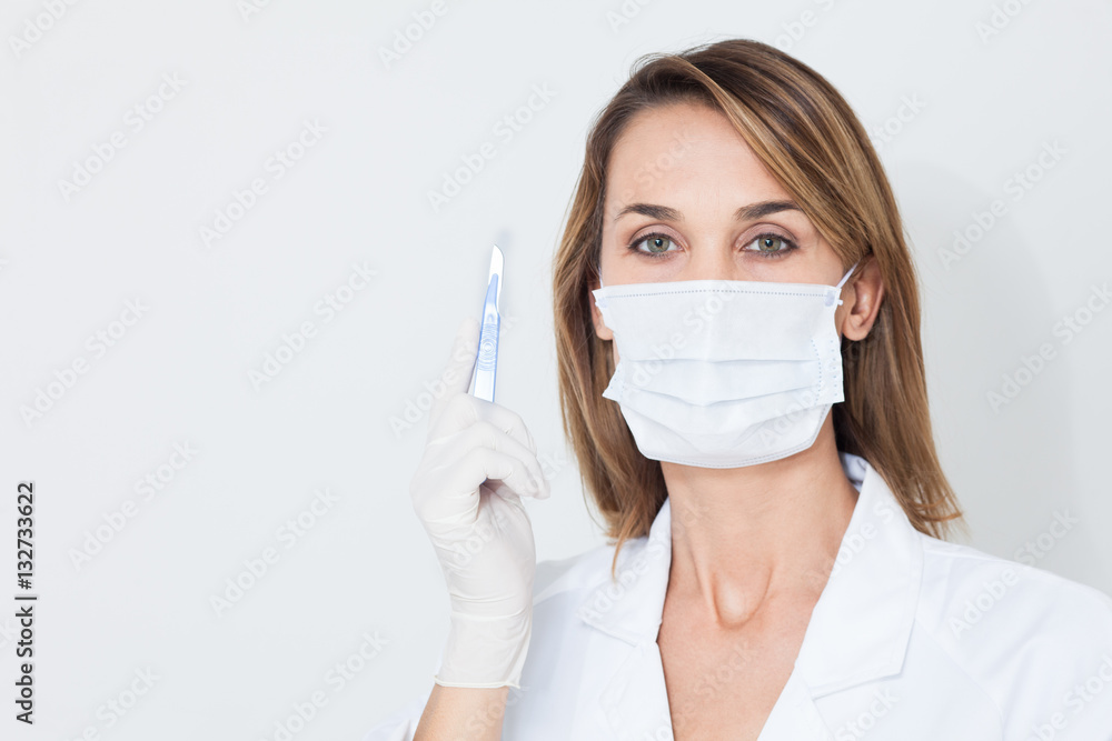 portrait de femme en blouse blanche avec un masque chirurgical et un bistouri portrait de femme en blouse blanche avec un masque chirurgical et un bistouri