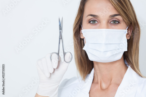 portrait de femme en blouse blanche avec un masque chirurgical et des ciseaux photo