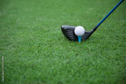 golf club and ball on a tee on a green grass