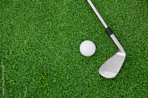 iron golf club and ball on a green grass