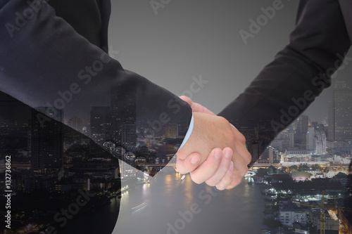 Businessman having a handshake over the city sunlight background
