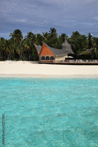 Bungalow complex in tropical paradise. Crystal blue water, white sand and palm grove, Maldives
