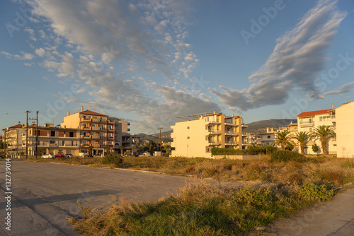 View on sunny city street with buildings at dawn. Nei Pori village, Pieria, Greece. 