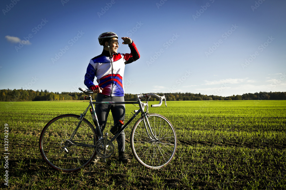 cyclist in the field next to the bicycle standing and looking forward for new horizonts on sunny day
