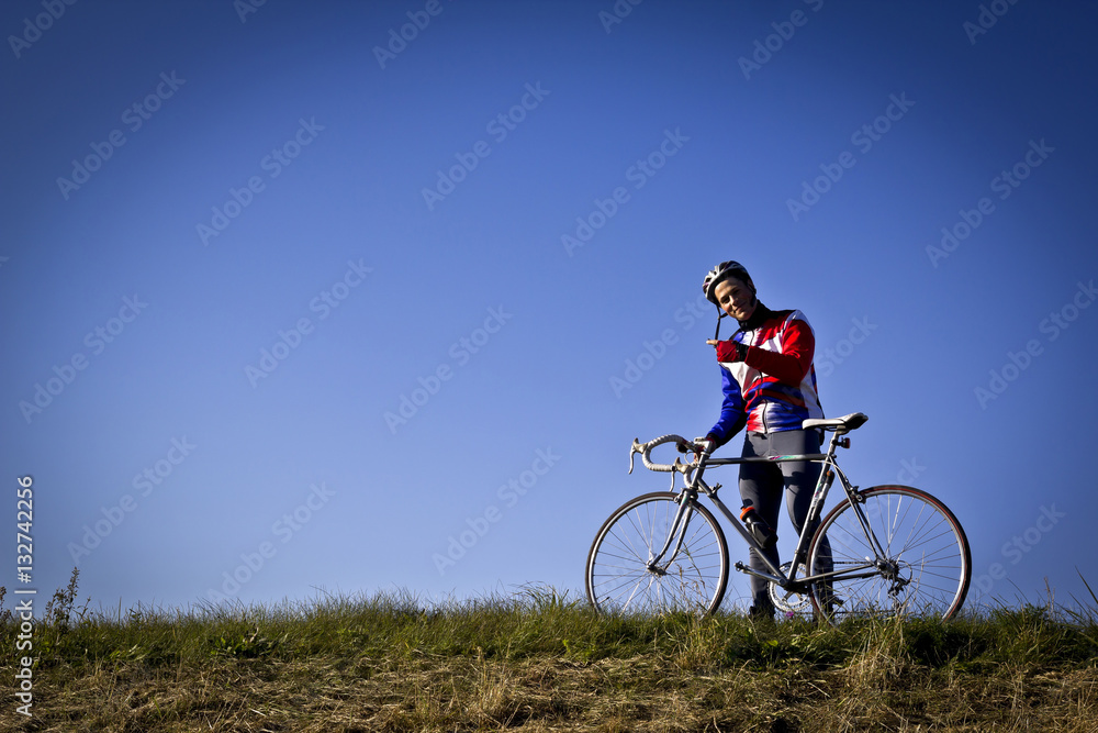 cyclist in the field next to the bicycle standing and looking forward for new horizonts on sunny day cyclist in the field next to the bicycle standing and looking forward for new horizonts on sunny day