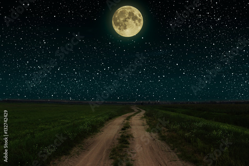 Beautiful magic night sky with fullmoon and stars road receding into the distance green grass © volhavasilevich