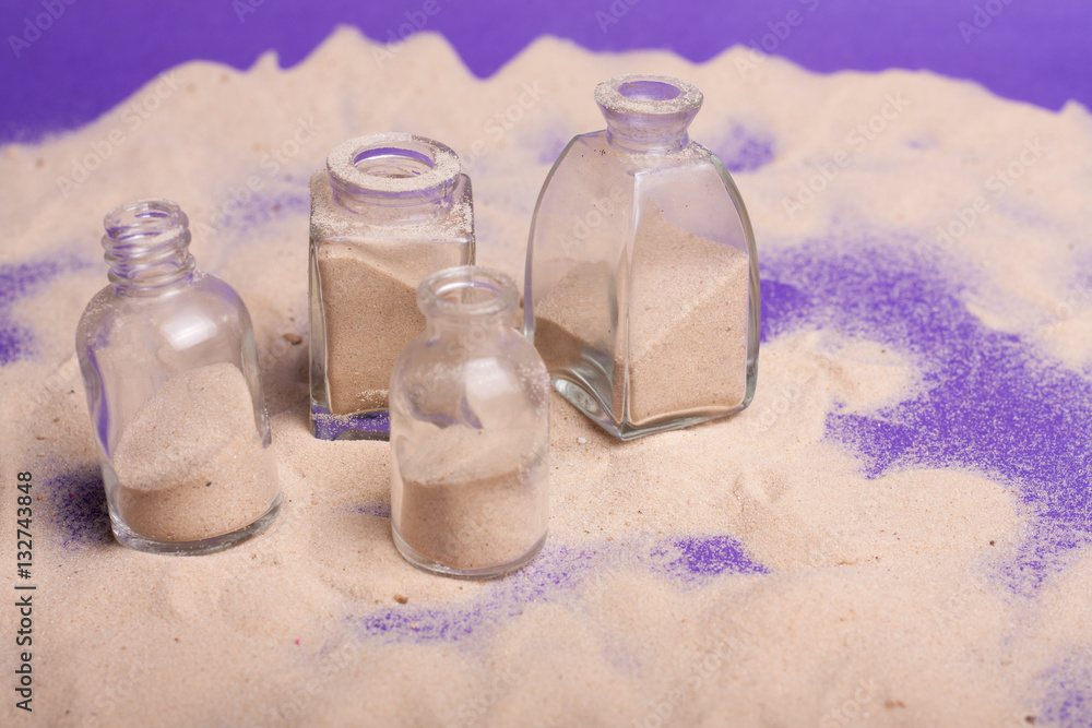 Obraz premium garrafas pequenas com areia em fundo roxo