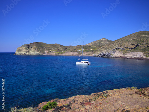 Catamaran sailing boat in small bay on blue sea. Santorini  Greece..