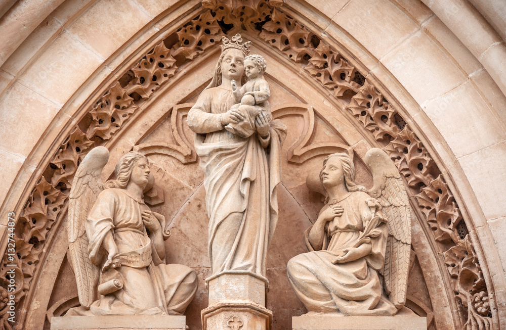 Sculpture of the Virgin Maria carrying a child surrounded by angels. Portal on the side-wall of Catedral de Santa Maria de Palma de Mallorca, one of the main sights of the Majorca island.