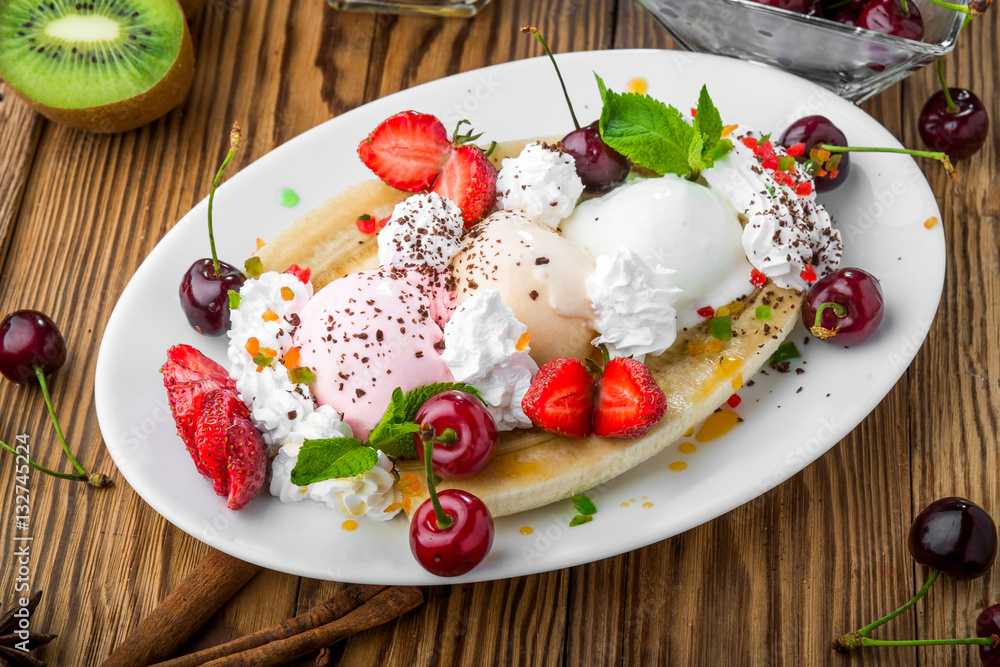 Banana split sundae ice cream in a bowl with strawberry and raspberry vanilla icecream scoops Banana split sundae ice cream in a bowl with strawberry and raspberry vanilla icecream scoops