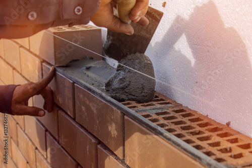 Fotótapéta Bricklayer lays the mortar for laying brick. construction work