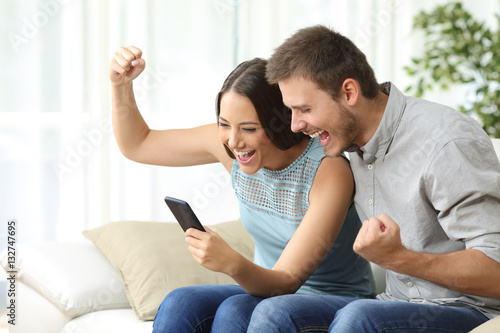 Excited couple watching media in a mobile phone