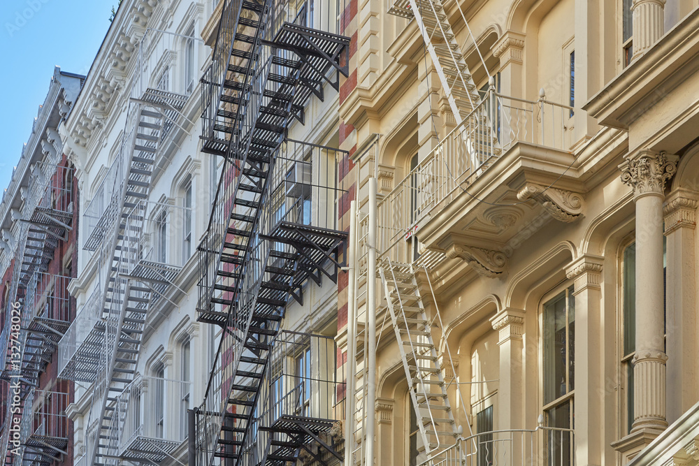 New York ancient buildings facades with fire escape stairs, sunny
