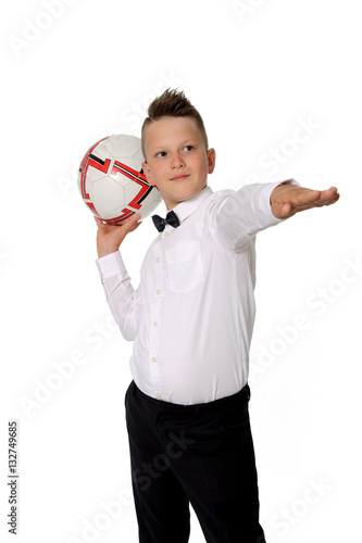 Młody chłopiec w białej koszuli trzyma piłkę na dłoni.