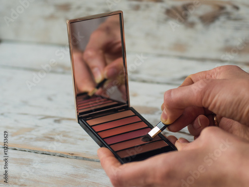 Woman holding a colorful lip palette and a brush, close up